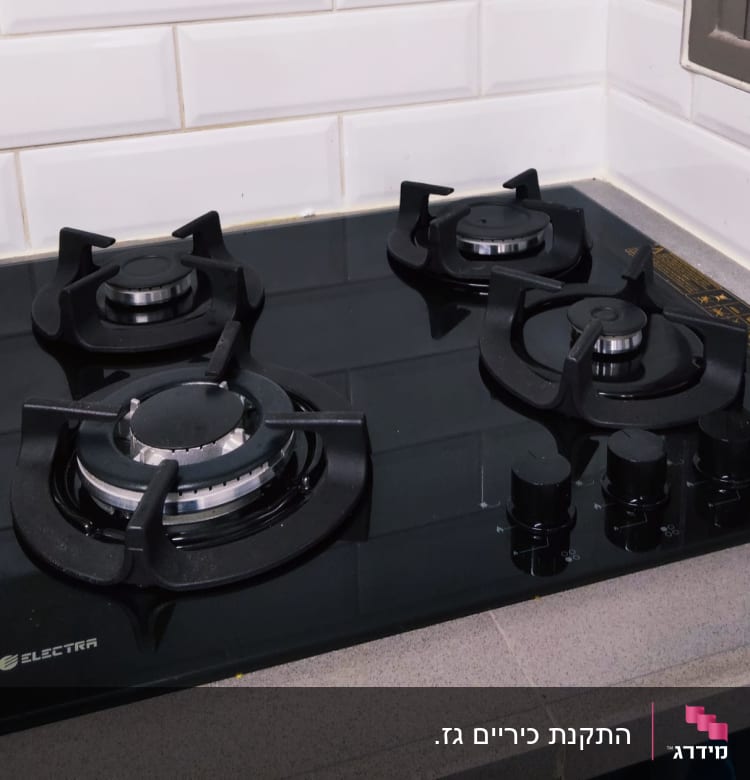 כיריים גז שחורות עם שלושה מבערים וכפתורי שליטה